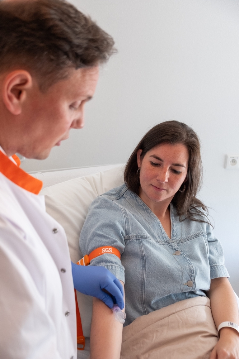 Verpleegkundige neemt een bloedstaal af bij een patiënt tijdens een klinische studie bij SGS Clinical Pharmacology Unit